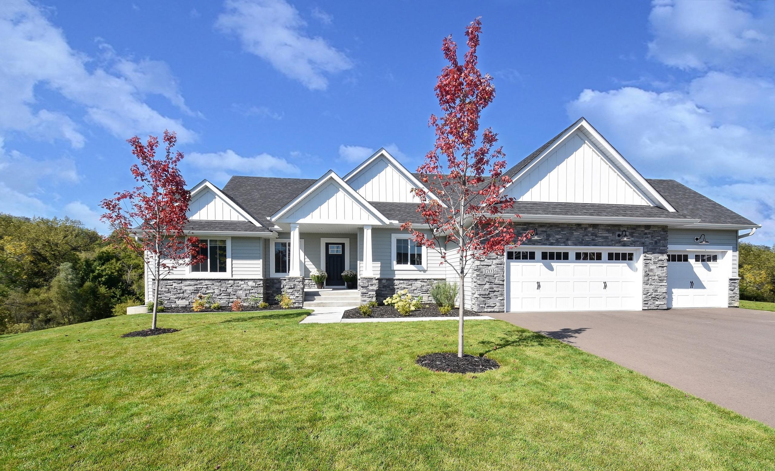 Contemporary home with gray siding, white gables, stone accents, and a dark roof