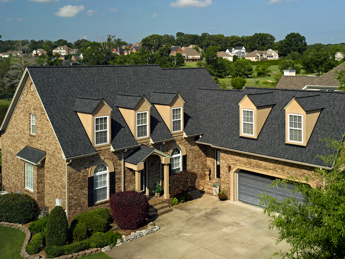 Dark architectural shingles across the roof and dormers of a brick home